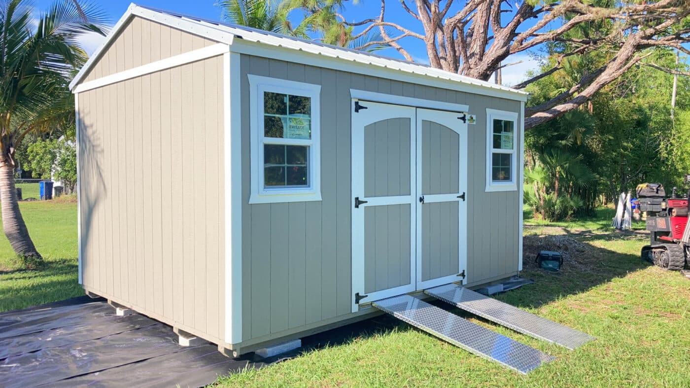 a beige shed with white trim and ramps attached in florida