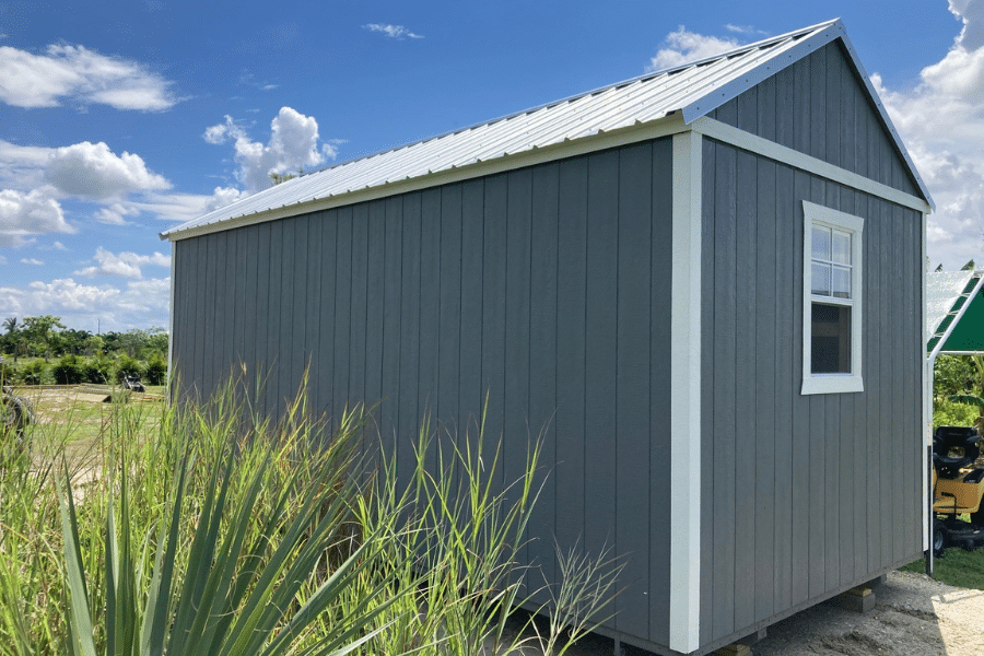 gray and white trimmed side lofted gable shed by plants