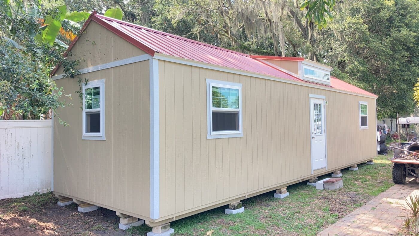 side gable lofted shed with three windows, white trim, and a red roof